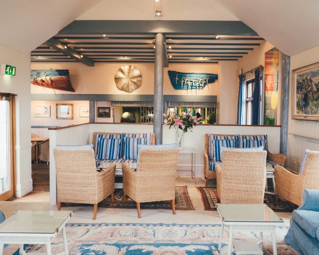 Hotel lounge with wicker armchairs, striped cushions and island art, Isles of Scilly